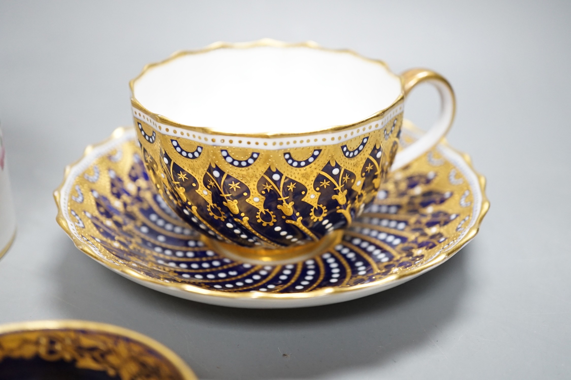 A 19th century Coalport fan shaped dish painted with a Loch scene, two small cup with twin handles decorated with raised gilding on a cobalt blue ground with crown marks, a Copeland jewelled cup and saucer with blue grou